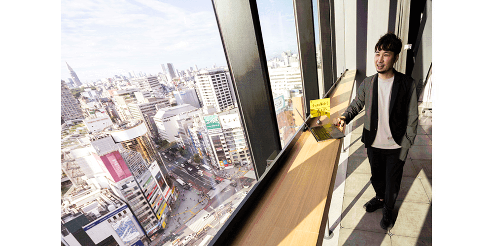 「渋谷から世界へ問いかける、可能性の交差点」SHIBUYA QWS（渋谷キューズ）を主な仕事場にしている横石氏。眼下にSSUの舞台となる渋谷の街を見渡せる。